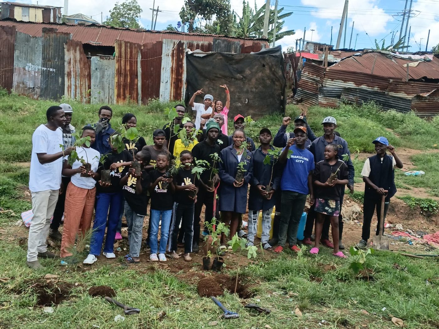 Youth and children holding seedlings at a community tree planting in Korogocho